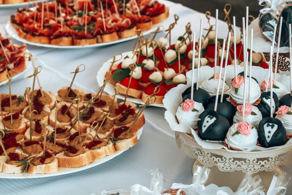An elegant display of appetizers with creatively decorated desserts at a wedding reception.