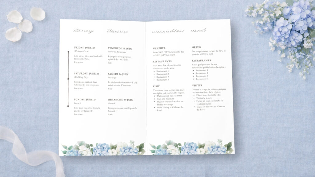 Flat lay of bilingual wedding weekend itinerary cards on blue linen with silk ribbon and blue florals with baby’s breath, styled for a destination wedding welcome suite.
